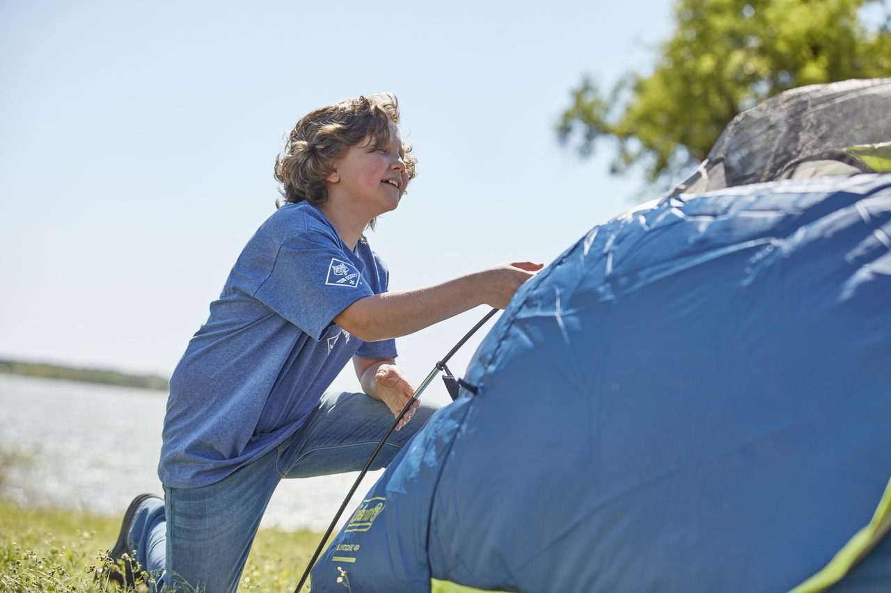 A scout helps a parent at the campsite.