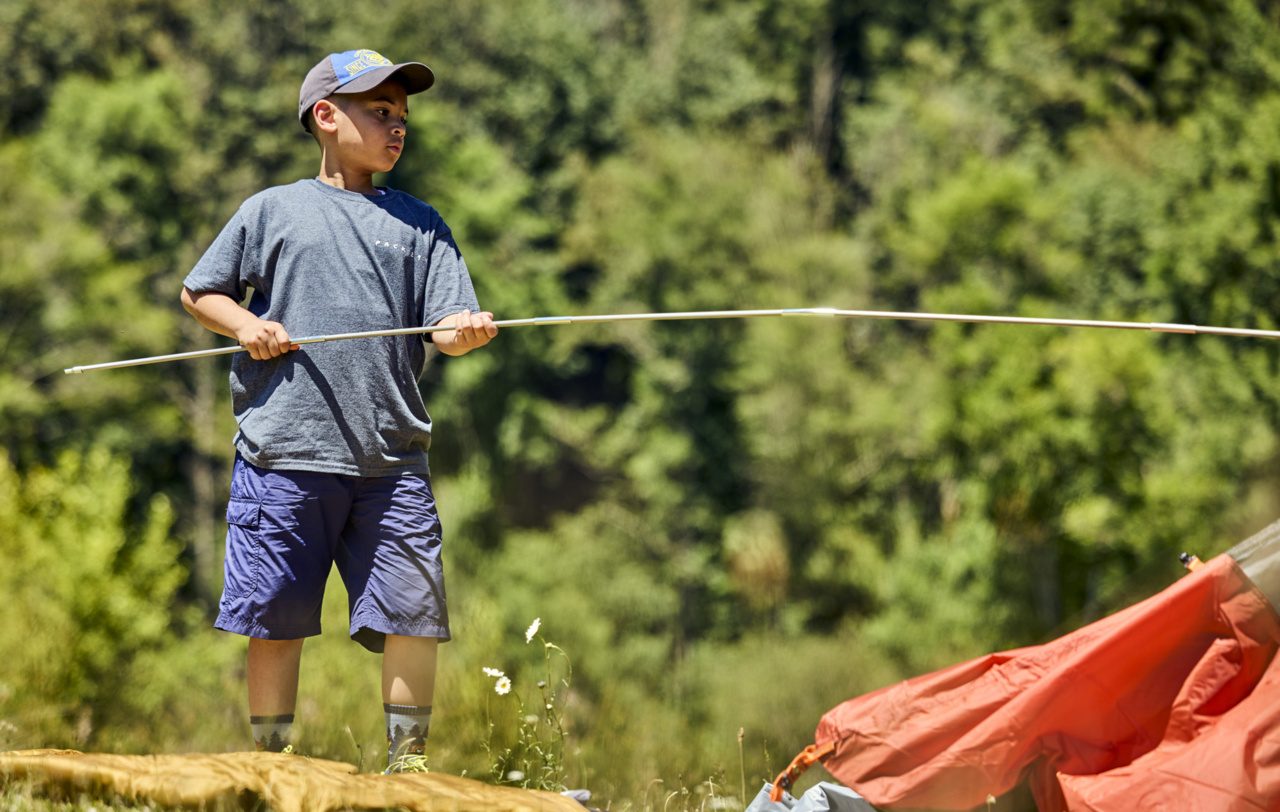 Cub Scout sets up tent poles at camp.