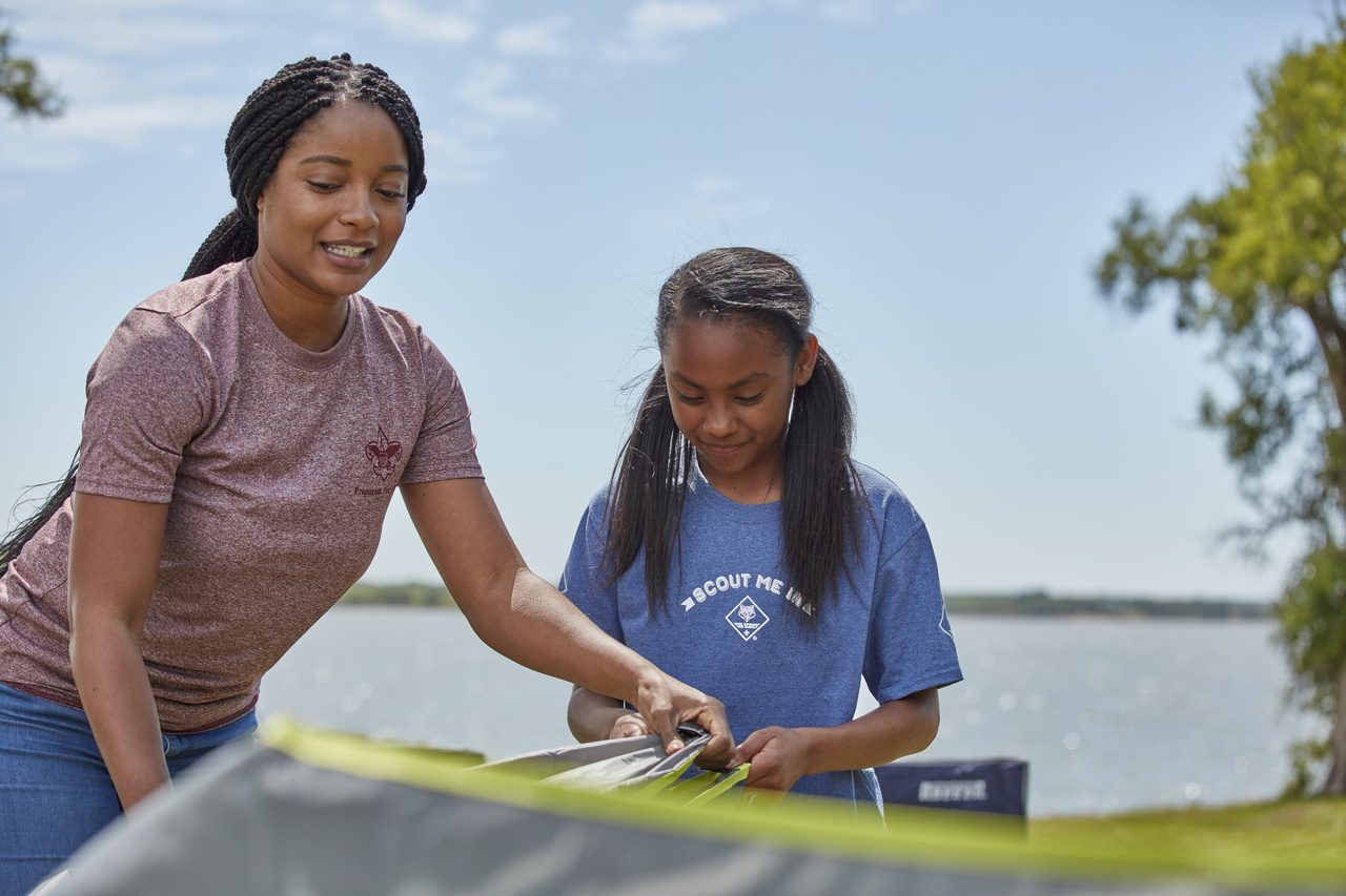 Pitching a tent by the lake at family camp.