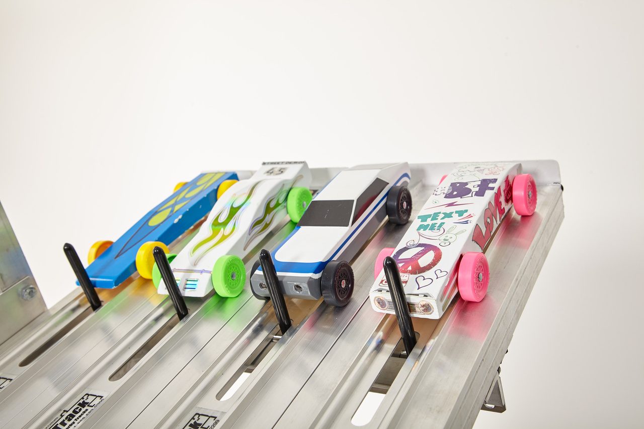 Four custom-painted Pinewood Derby cars on the track.